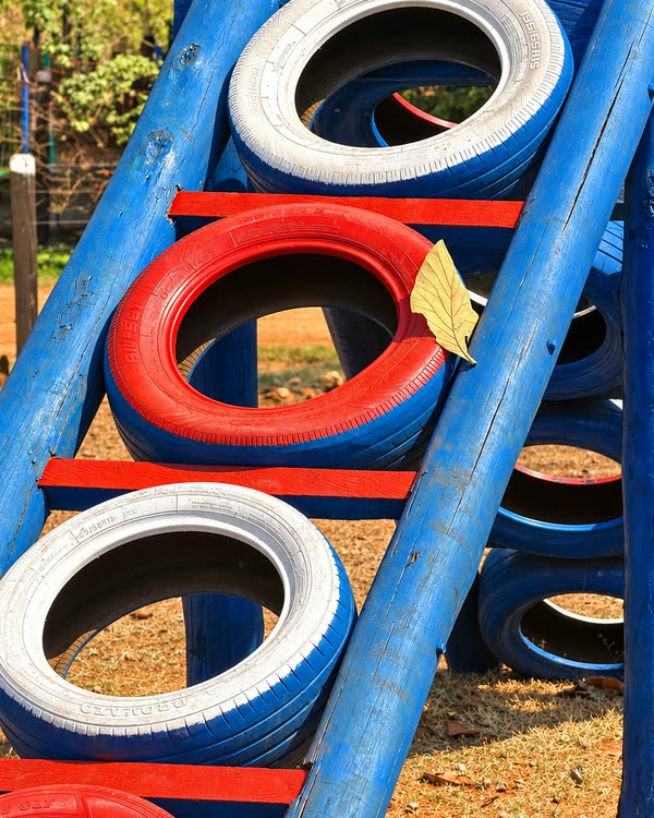Escada de toras azuis com pneus pintados de branco e de vermelho